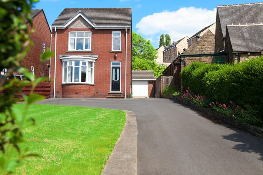 Detached house made of red bricks with long concrete driveway